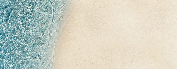 beautiful abstract sand beach from above with water and sand texture in sunshine, clean empty nature background with copy space for your advertising and product presentation
